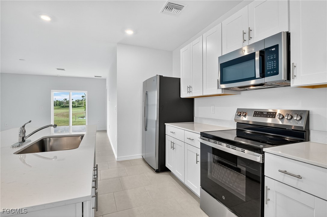 19778 Garden Ridge Lehigh Acres, FL 33936 - Photo 18 of 31 a kitchen with stainless steel appliances a stove a microwave and a sink