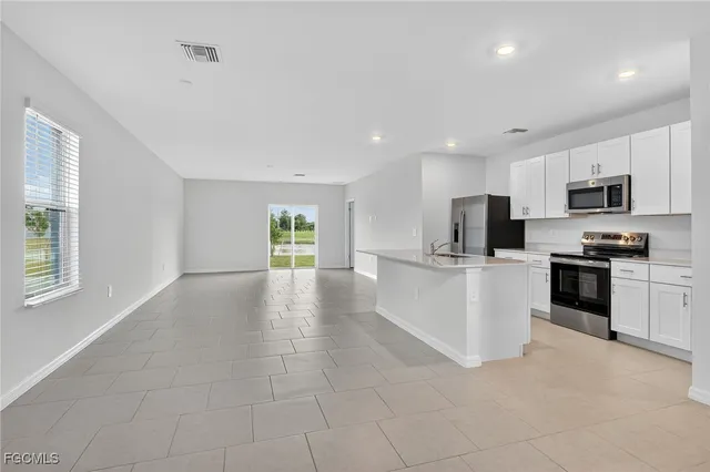 a view of kitchen with granite countertop stove top oven and refrigerator