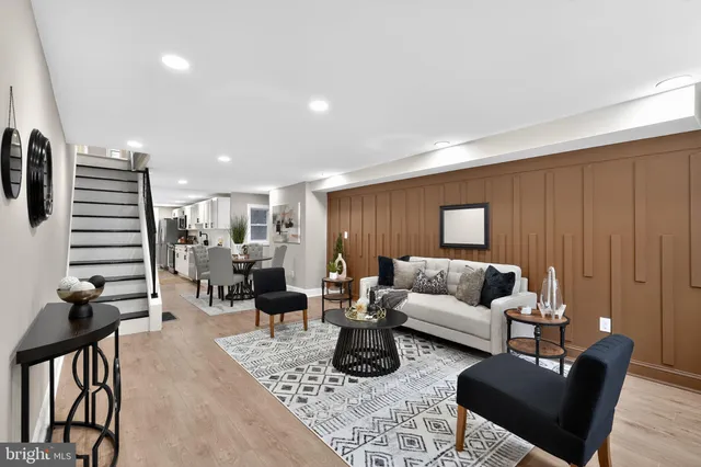 a living room with furniture kitchen view and a wooden floor