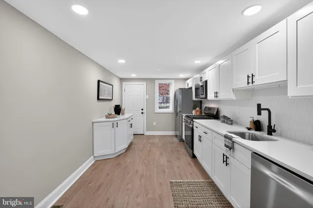 a kitchen with white cabinets appliances and a sink