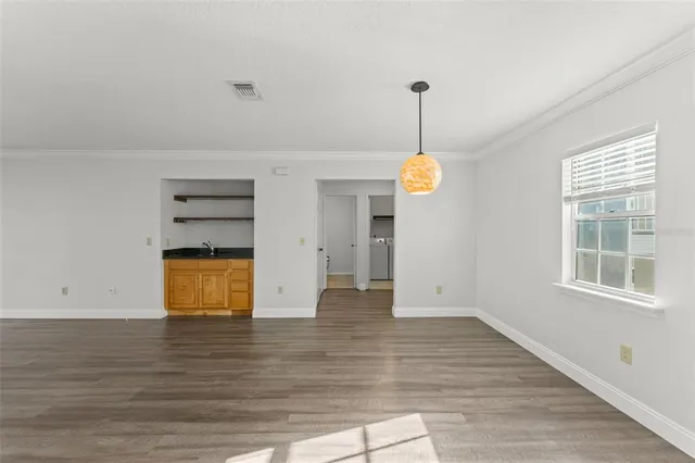 a view of an empty room with a window and wooden floor