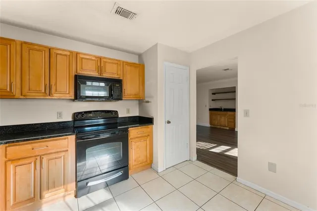 a kitchen with granite countertop a refrigerator and a stove top oven