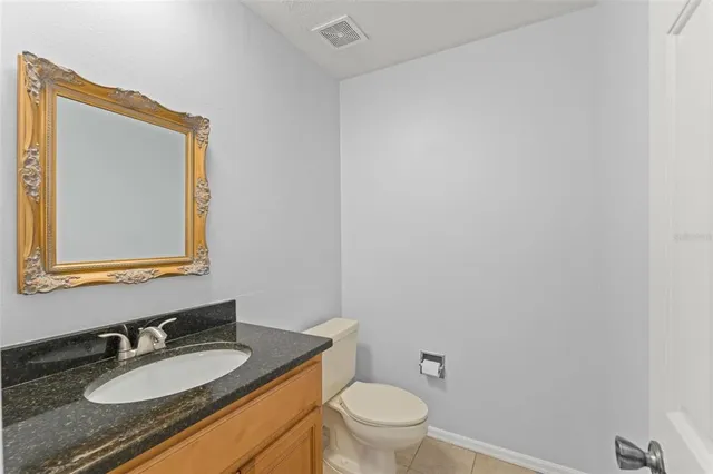 a bathroom with a granite countertop sink vanity mirror and toilet