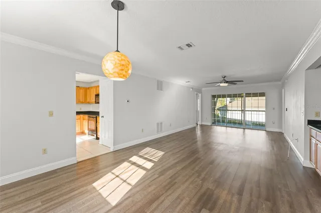 a view of empty room with wooden floor and fan