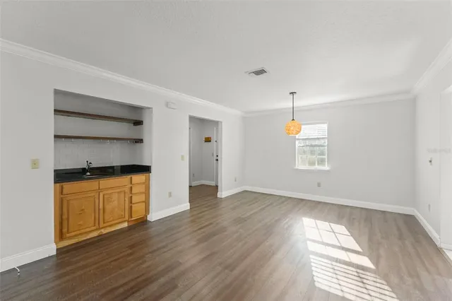 an empty room with wooden floor cabinet and windows
