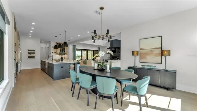 a view of a dining room and livingroom with furniture wooden floor a chandelier