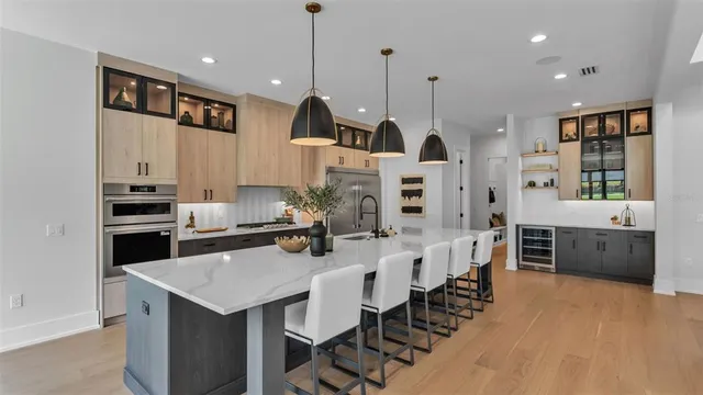 a large kitchen with kitchen island a island a stove a sink a counter space and stainless steel appliances