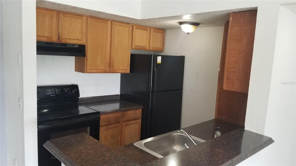 5160 Conroy Road, Unit 1437 Orlando, FL 32811 - Photo 14 of 36 a kitchen with a sink and a refrigerator