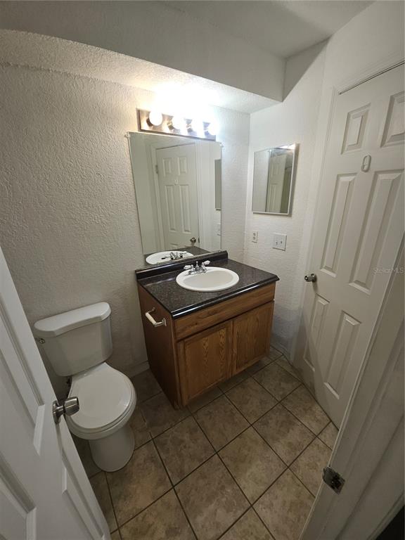 5160 Conroy Road, Unit 1437 Orlando, FL 32811 - Photo 24 of 36 a bathroom with a granite countertop sink a toilet a mirror and shower