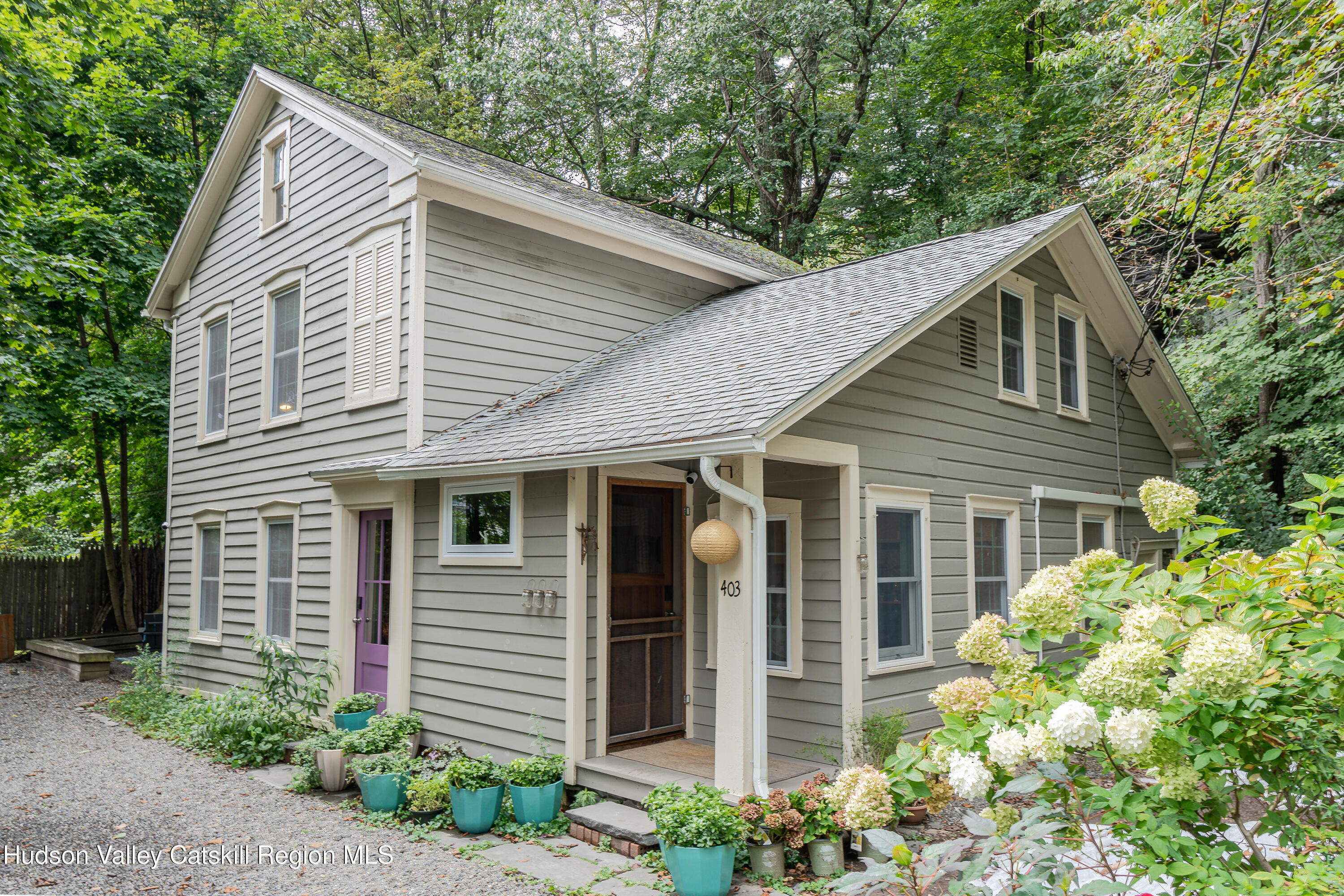 a small white house with a white roof and table and chairs next to window