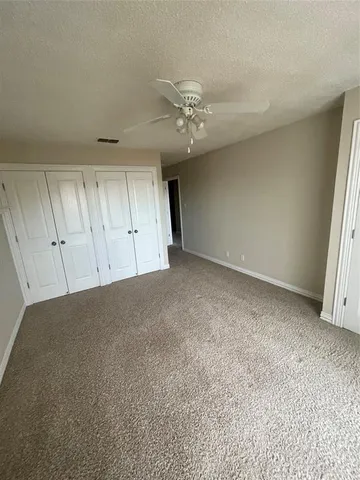 an empty room with a ceiling fan and window