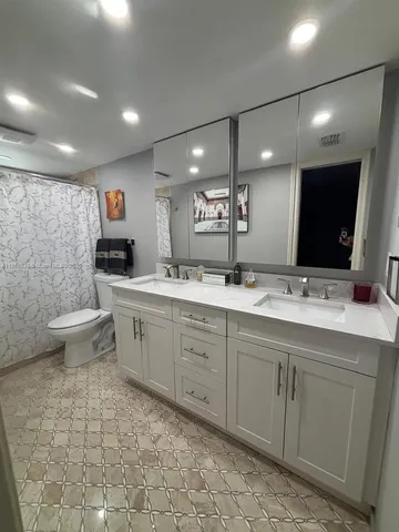 a spacious bathroom with a double vanity sink a toilet mirror and a bathtub