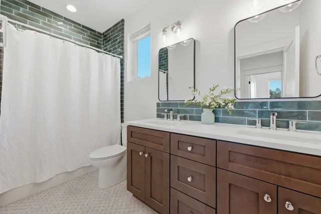 a bathroom with a double vanity sink toilet and mirror