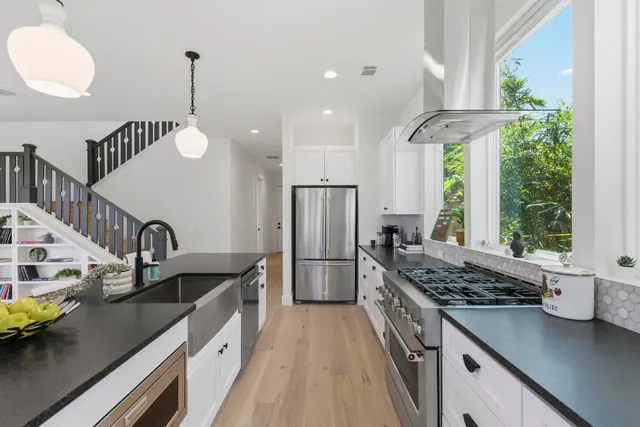 a kitchen with stainless steel appliances granite countertop a sink a stove and a wooden floors