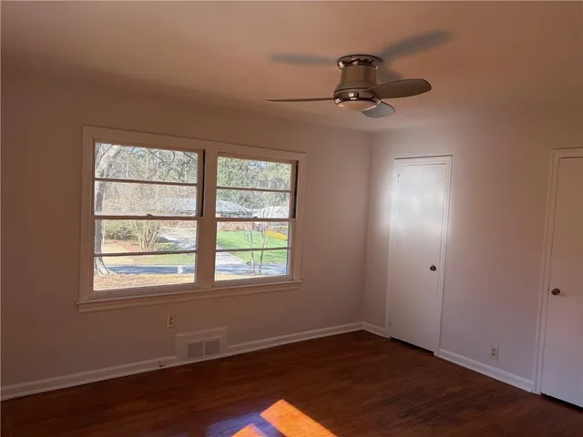 an empty room with wooden floor cabinet and windows