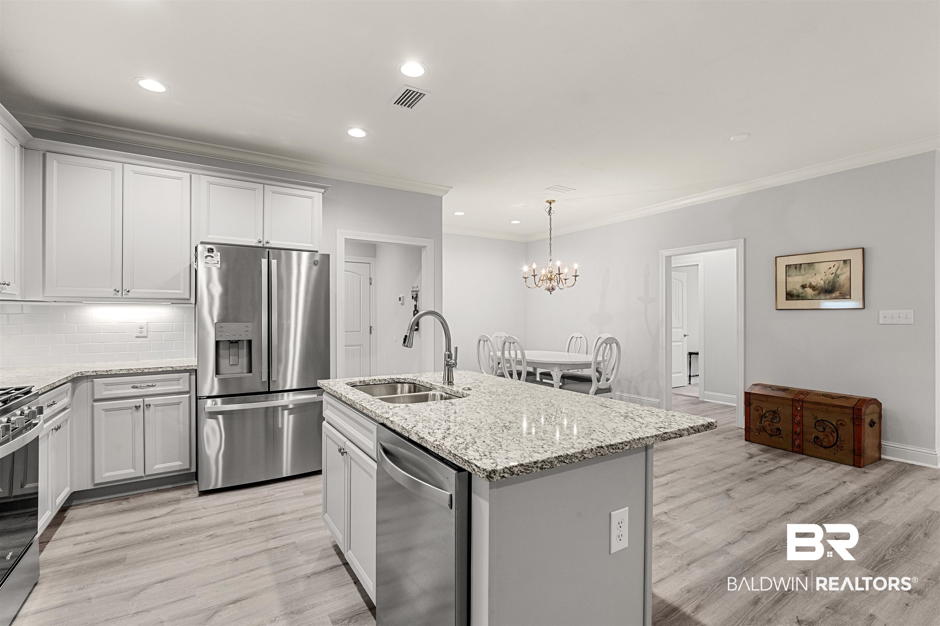 702 Holmes Avenue, Unit 702 Foley, AL 36535 - Photo 7 of 33 Kitchen with stainless steel appliances, sink, white cabinetry, pendant lighting, and a kitchen island with sink