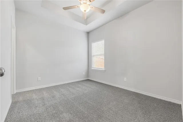 an empty room with a chandelier fan and windows