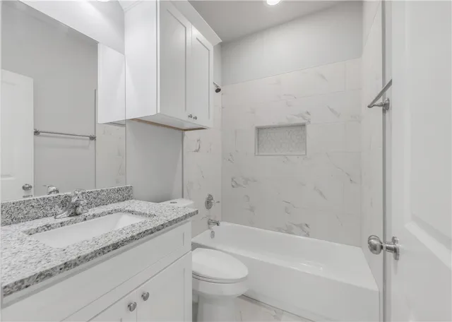 a bathroom with a granite countertop sink a toilet and bathtub