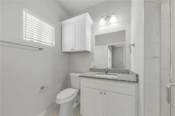 a bathroom with a granite countertop toilet sink and mirror