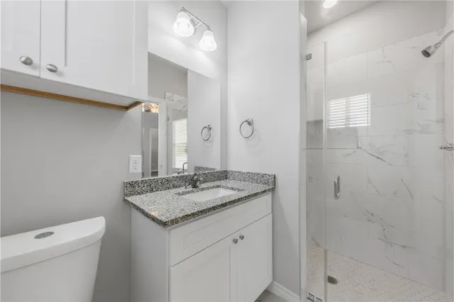 a bathroom with a granite countertop sink a toilet and a mirror
