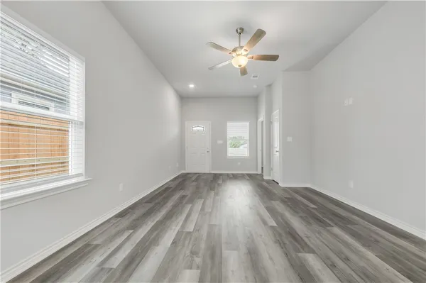 a view of an empty room with wooden floor and window