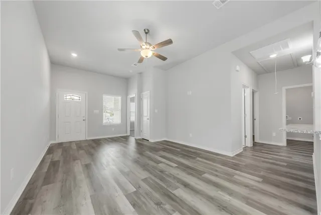 an empty room with wooden floor and windows
