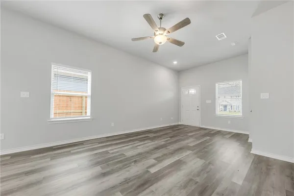 an empty room with wooden floor and windows