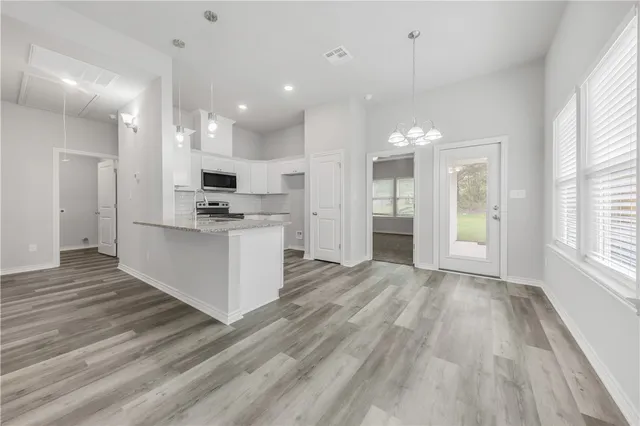a view of a kitchen with kitchen island a sink stainless steel appliances and cabinets