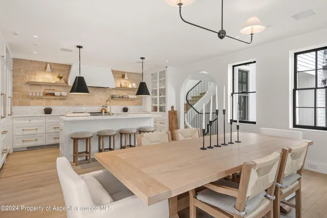 a dining room with wooden floor a chandelier a wooden table and chairs