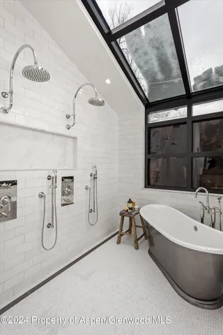 a bathroom with a tub a sink and mirror