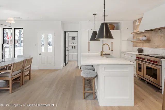 a kitchen with kitchen island a stove a sink a dining table and chairs