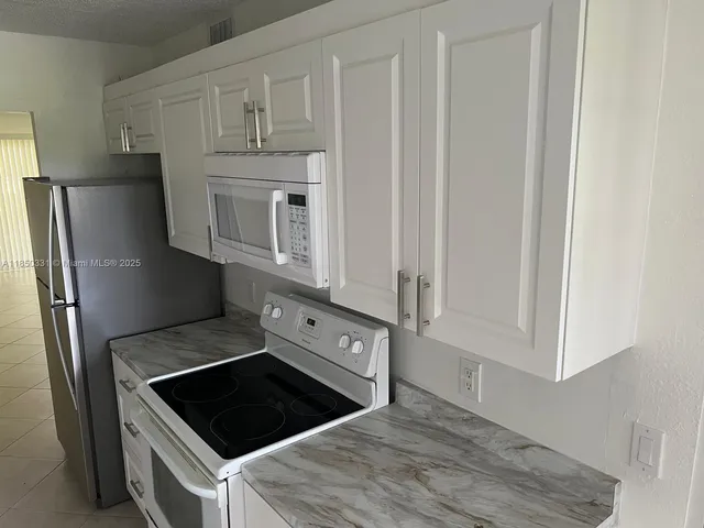 a kitchen with granite countertop white cabinets and refrigerator
