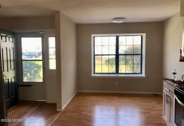 a view of an empty room with a window and wooden floor