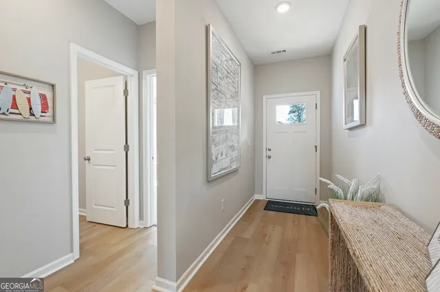 a view of a hallway to a livingroom with wooden floor and a bathroom
