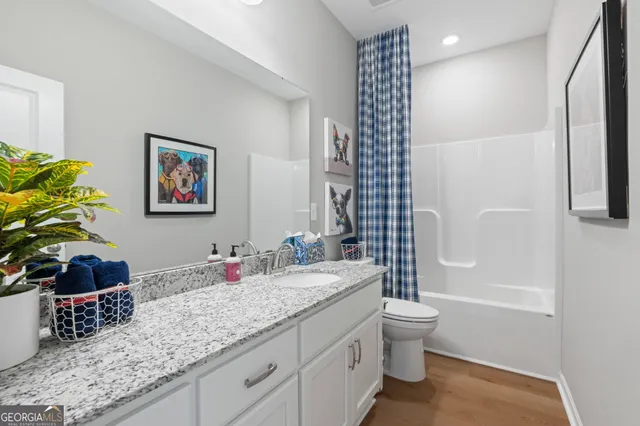 a bathroom with a granite countertop sink a toilet and shower