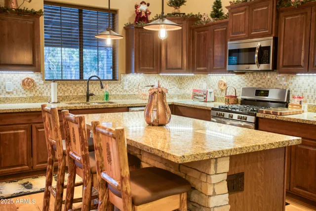 a kitchen with stainless steel appliances granite countertop a sink a stove and cabinets