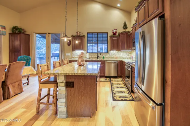 a kitchen with kitchen island granite countertop a refrigerator and a stove top oven