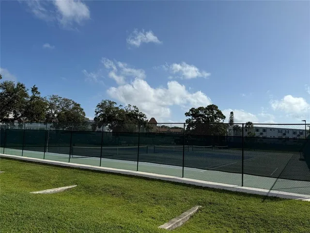 a view of swimming pool with lawn chairs and large trees