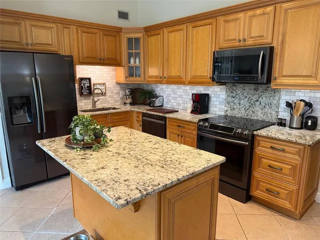 a kitchen with stainless steel appliances kitchen island granite countertop a stove refrigerator and microwave