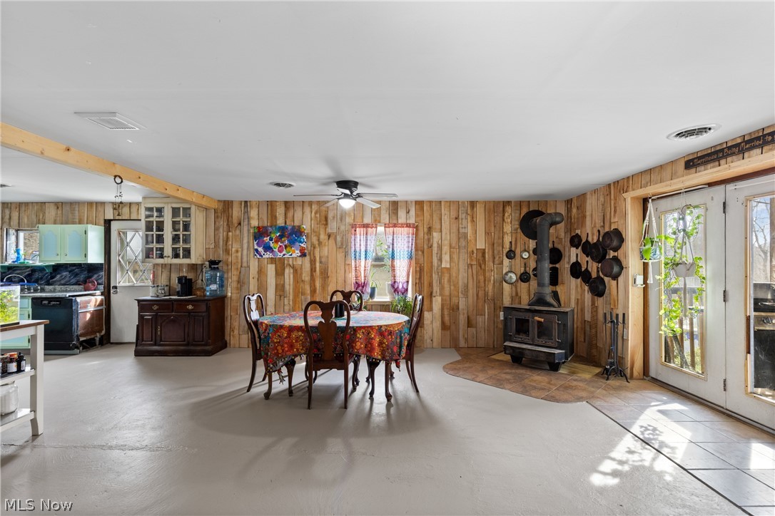 38340 Lees Run Road Cadiz, OH 43907 - Photo 6 of 31 Dining room featuring ceiling fan, a wood stove, & wood walls