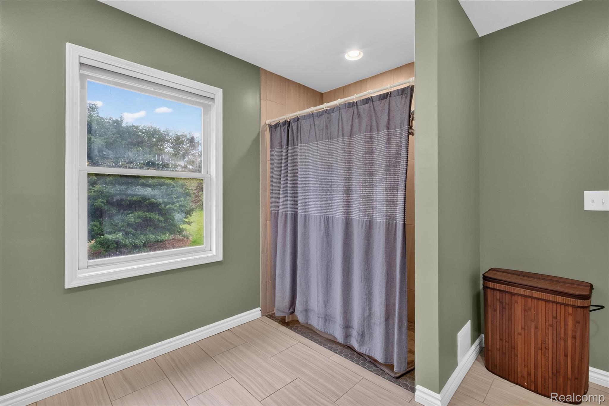 8114 Chilson Road Pinckney, MI 48169 - Photo 14 of 32 Windowed bathroom featuring wood-finish tile flooring, a recessed shower with tile surround, and a double-hung window