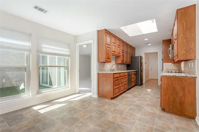 a large kitchen with stainless steel appliances kitchen island granite countertop a refrigerator and a sink