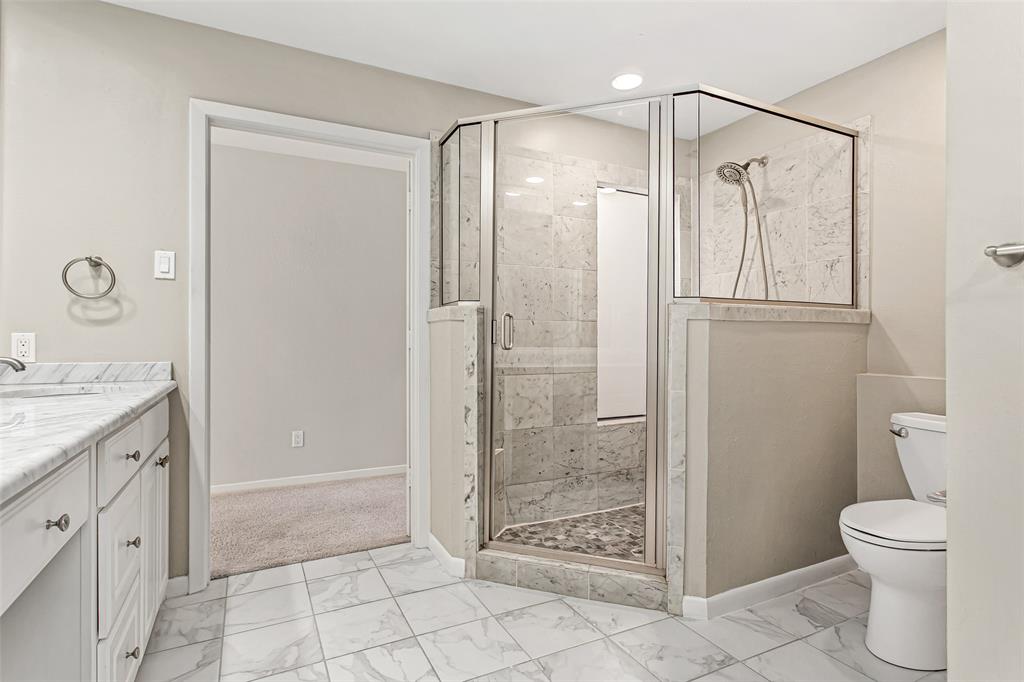 6807 Anglebluff Circle Dallas, TX 75248 - Photo 23 of 28 a bathroom with a granite countertop shower a mirror and a toilet