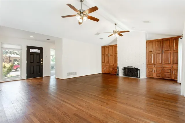 a view of an empty room with a ceiling fan and wooden floor