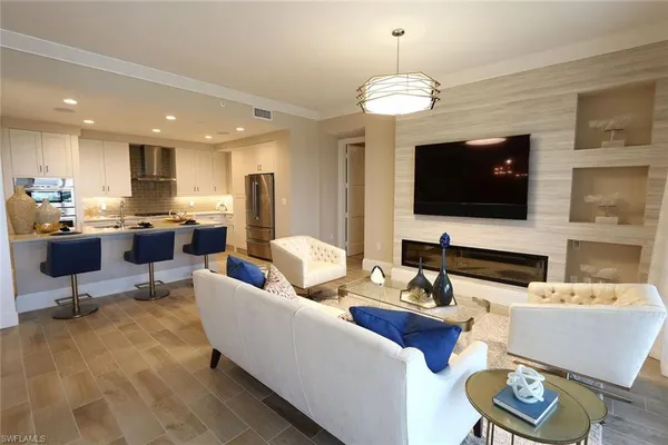 a living room with furniture a flat screen tv and kitchen view