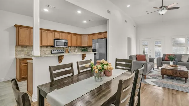 a living room with stainless steel appliances furniture a dining table and chairs