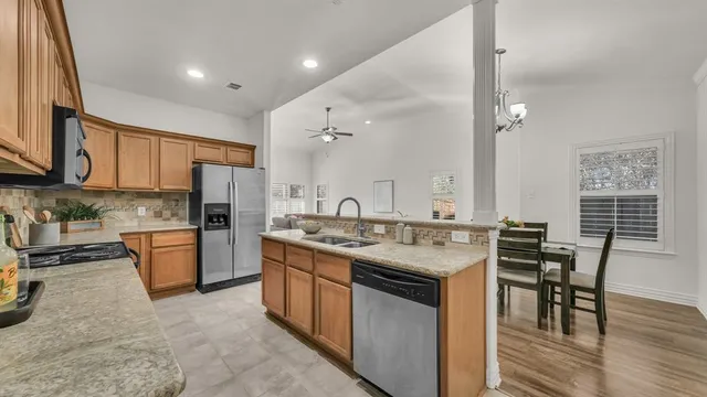 a kitchen with stainless steel appliances granite countertop a stove top oven a sink dishwasher a dining table and chairs with wooden floor