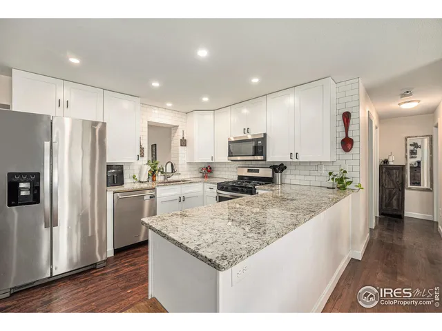 a kitchen with stainless steel appliances granite countertop a refrigerator a stove and a sink