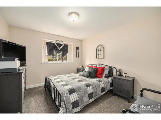 a bedroom with a bed a flat screen tv and dresser