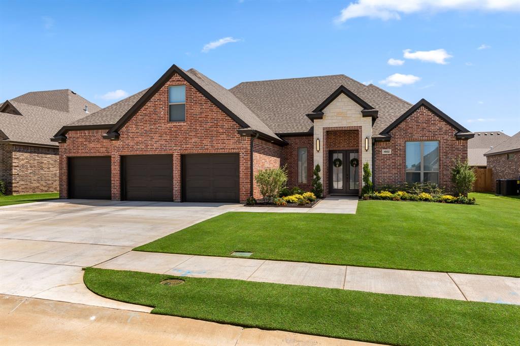 French country style house featuring roof with shingles, brick siding, concrete driveway, and a front yard